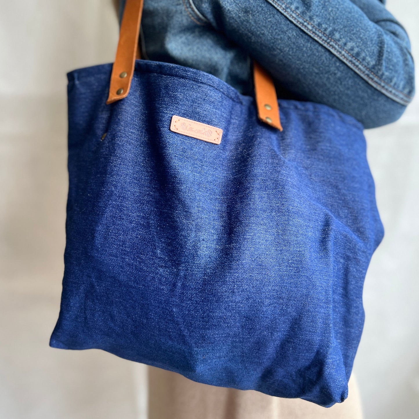 modelled view of soft slouchy denim tote with soft suede leather handles, handmade by Tallulah Riley