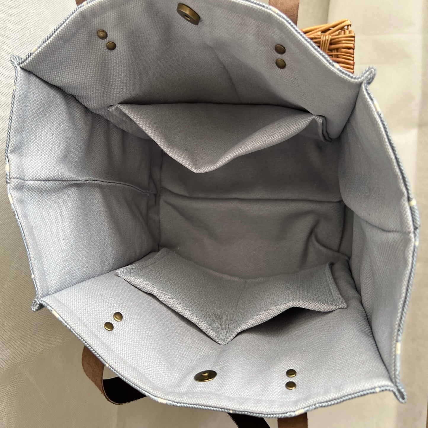 inside view of blue and crem boxy tote, grey lining with 3 internal pockets, antique brass studs and magnetic fastening, handmade by Tallulah Riley