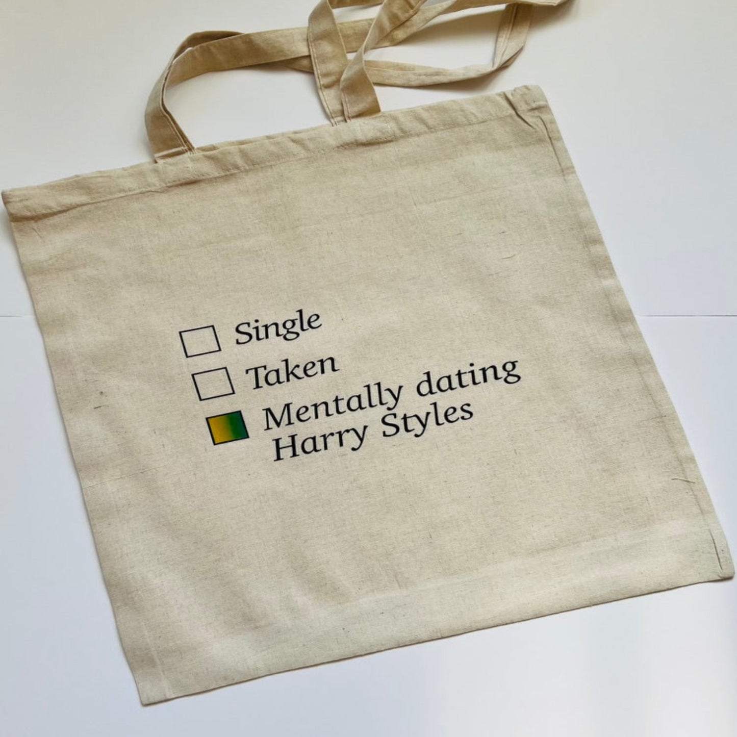 Natural tote bag with text and tick box stating mentally dating Harry Styles, handmade by Tallulah Riley