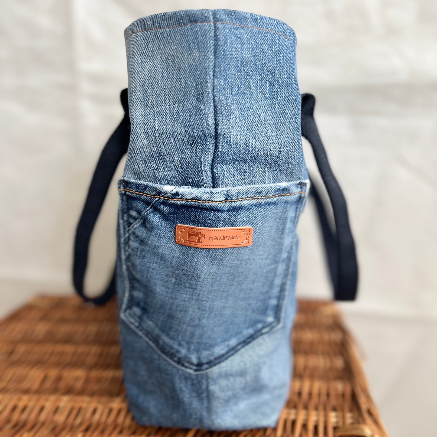 side view of upcycled, re-used denim jeans tote bag with side pockets and navy blue handles, handmade by Tallulah Riley
