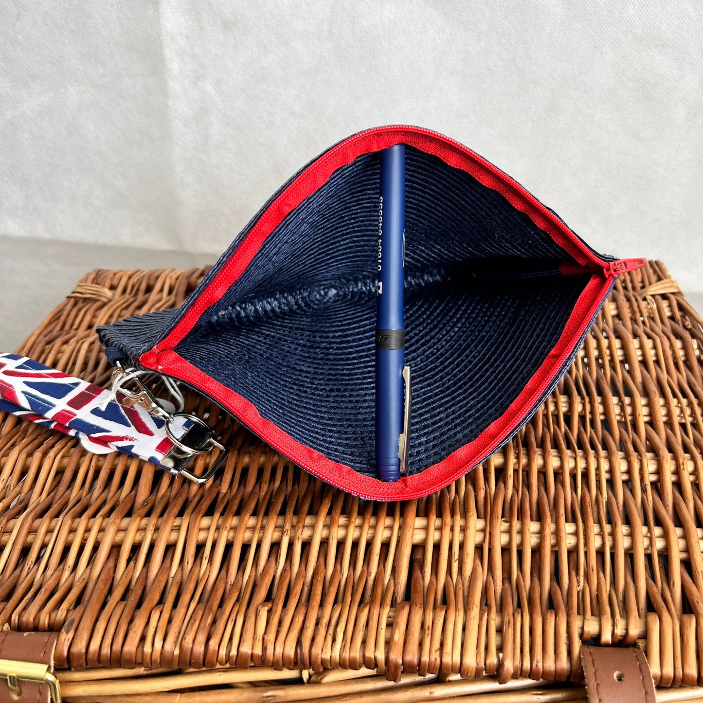 inside view of navy blue woven clutch bag with red zip and detachable union jack print wristlet, handmade by Tallulah Riley