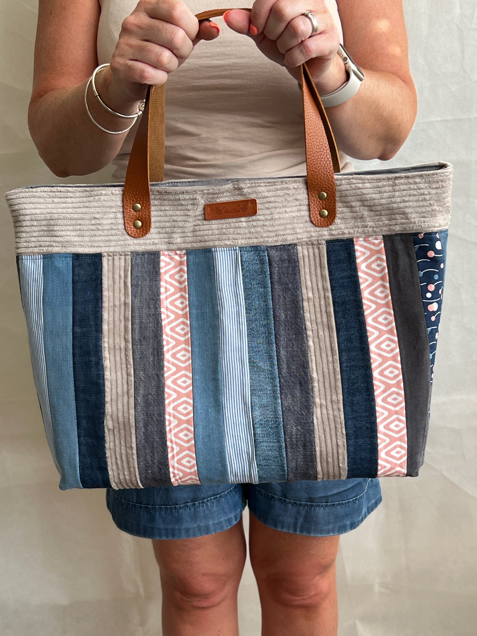 Modelled view of upcycled tote bag made from denim, corduroy and cotton fabric scraps with leather handles, handmade by Tallulah Riley