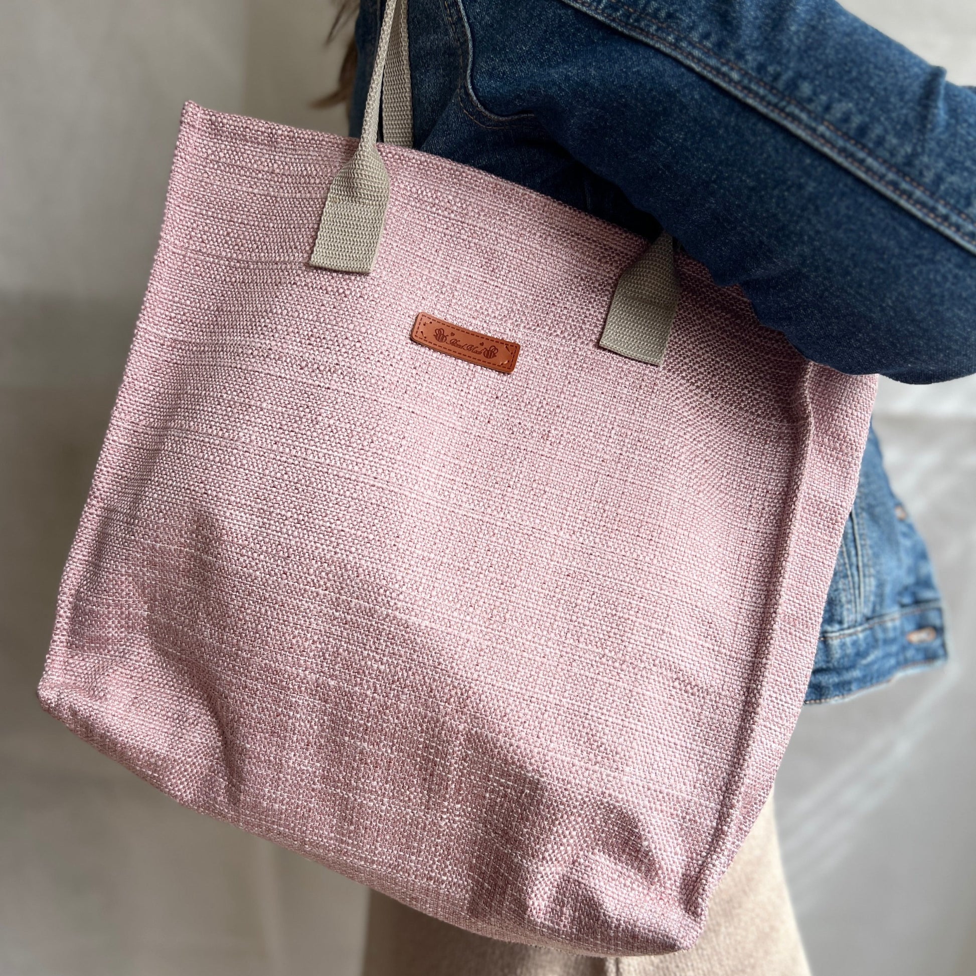 Modelled view of pink tweed style boxy tote bag with beige handles. Handmade by Tallulah Riley