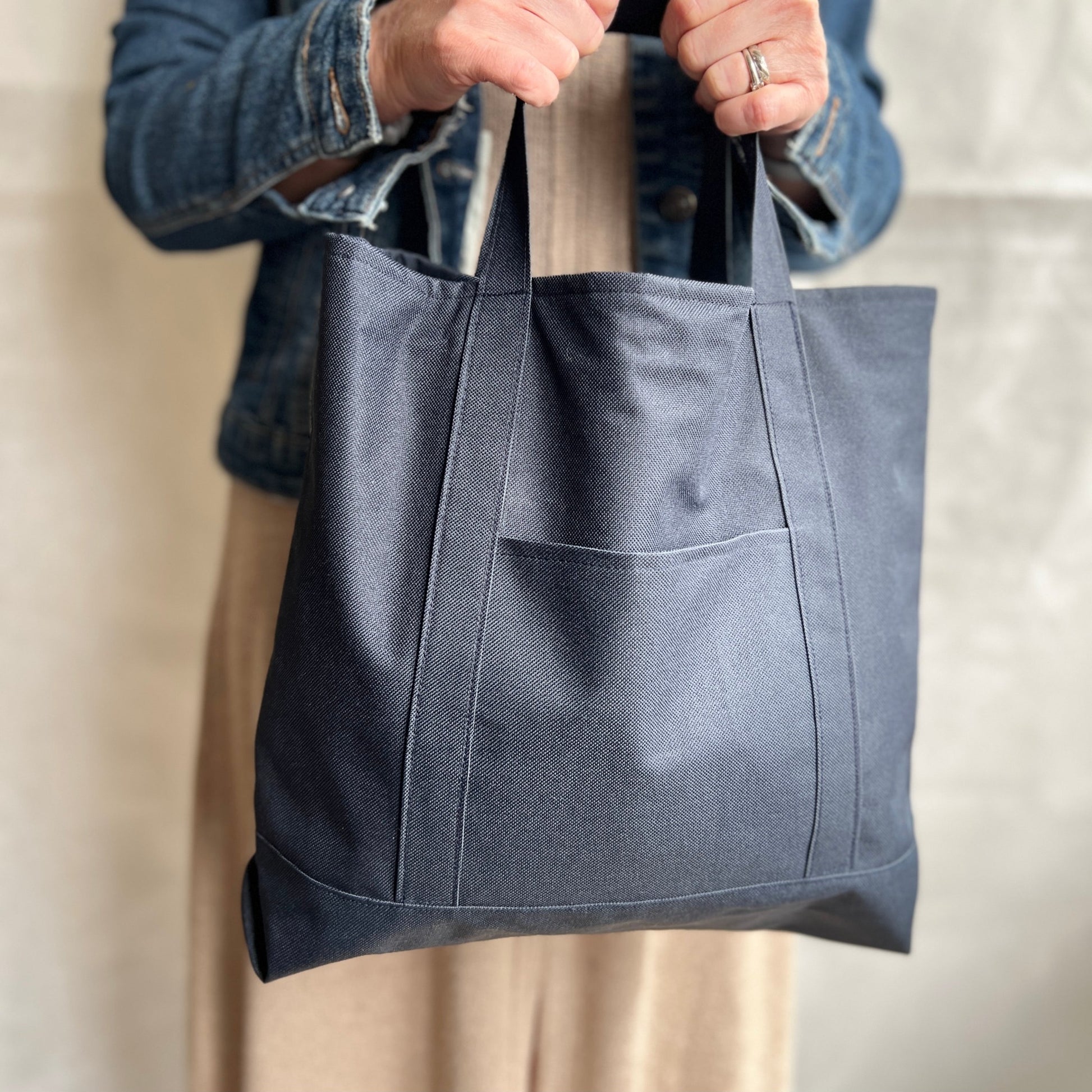 Modelled view, navy blue, waterproof canvas, strong, tote bag with short handles and outer pocket , handmade by Tallulah Riley