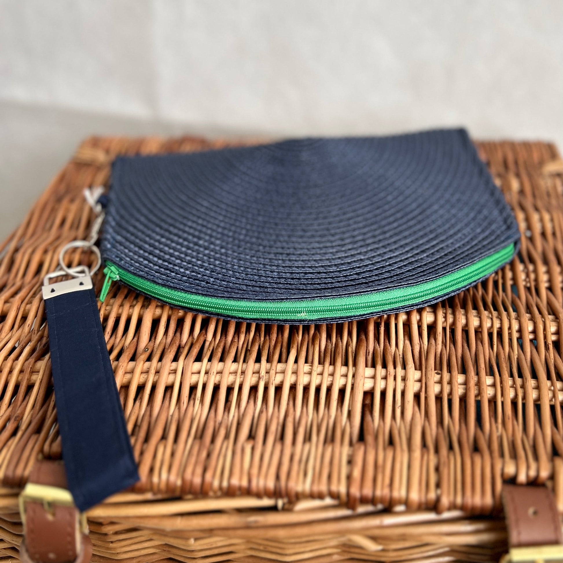 front view of navy blue woven clutch bag with green zip and navy blue detachable wristlet, handmade by Tallulah Riley