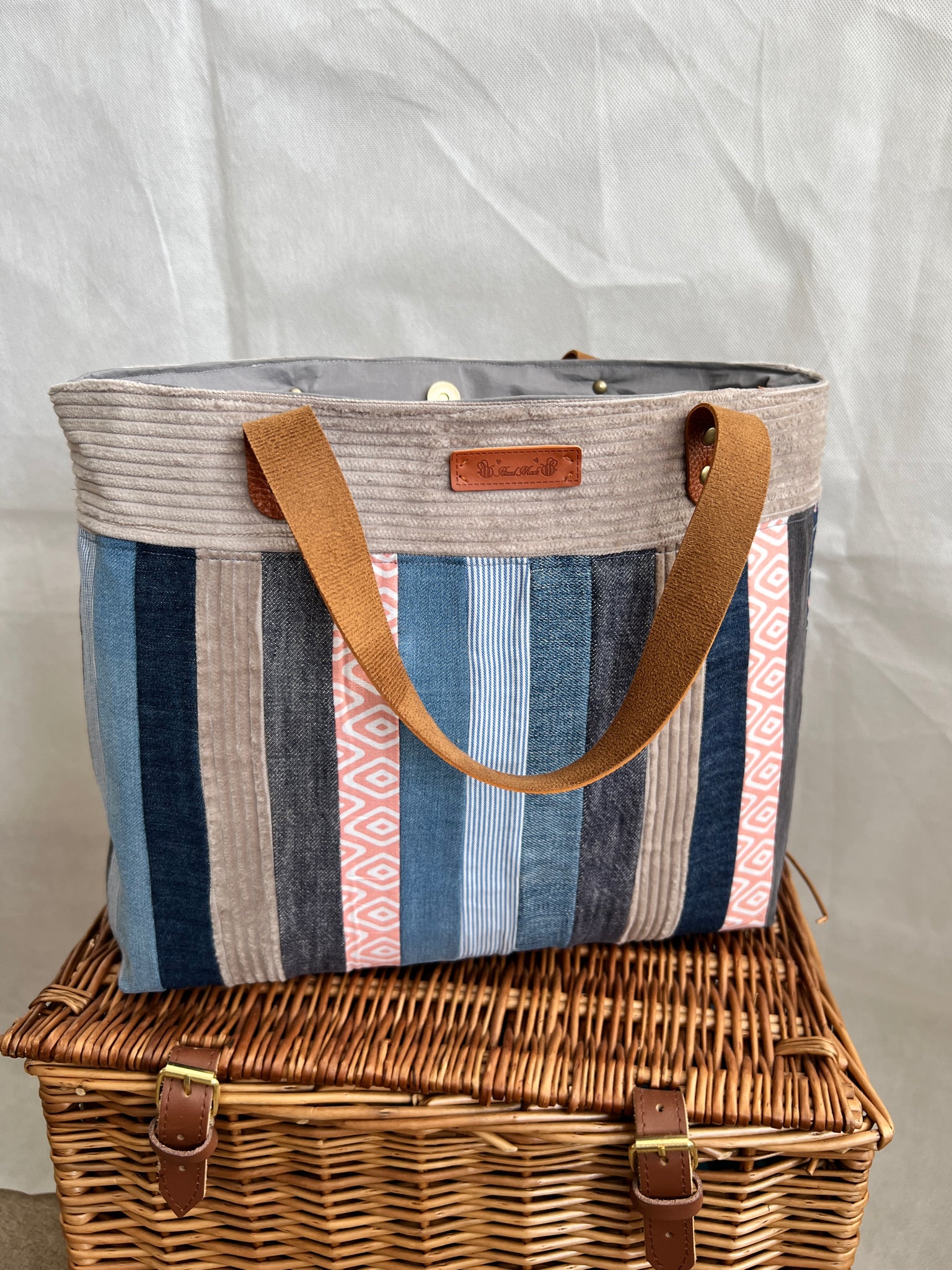 Front view of upcycled tote bag made from denim, corduroy and cotton fabric scraps with leather handles, handmade by Tallulah Riley