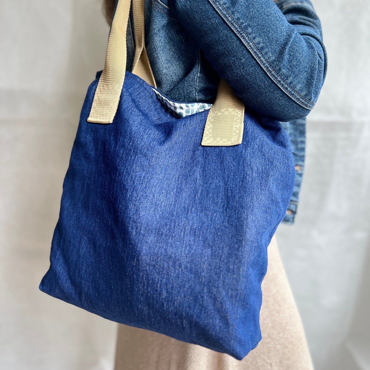 Modelled view of soft denim slouchy tote bag with beige handles, handmade by Tallulah Riley