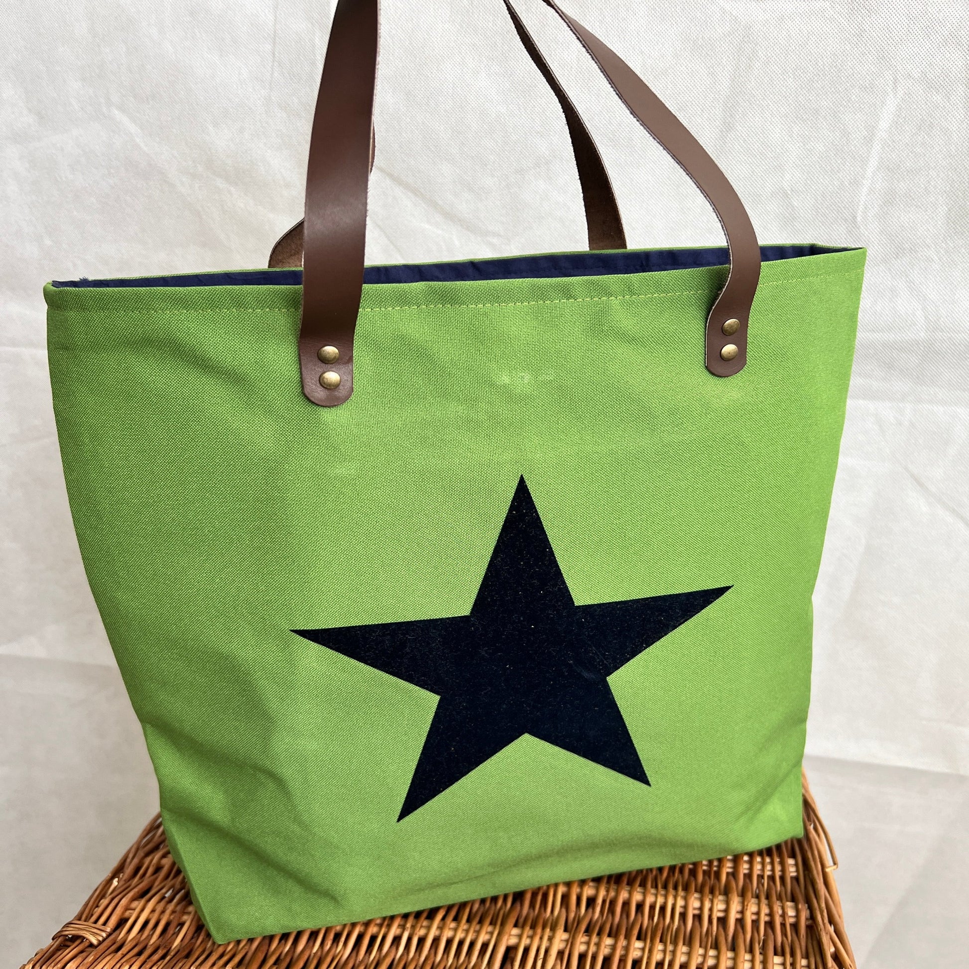 front view of bright green tote bag with navy blue star on front, brown leather handles, handmade by Tallulah Riley