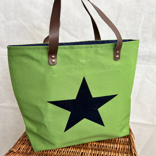 front view of bright green tote bag with navy blue star on front, brown leather handles, handmade by Tallulah Riley