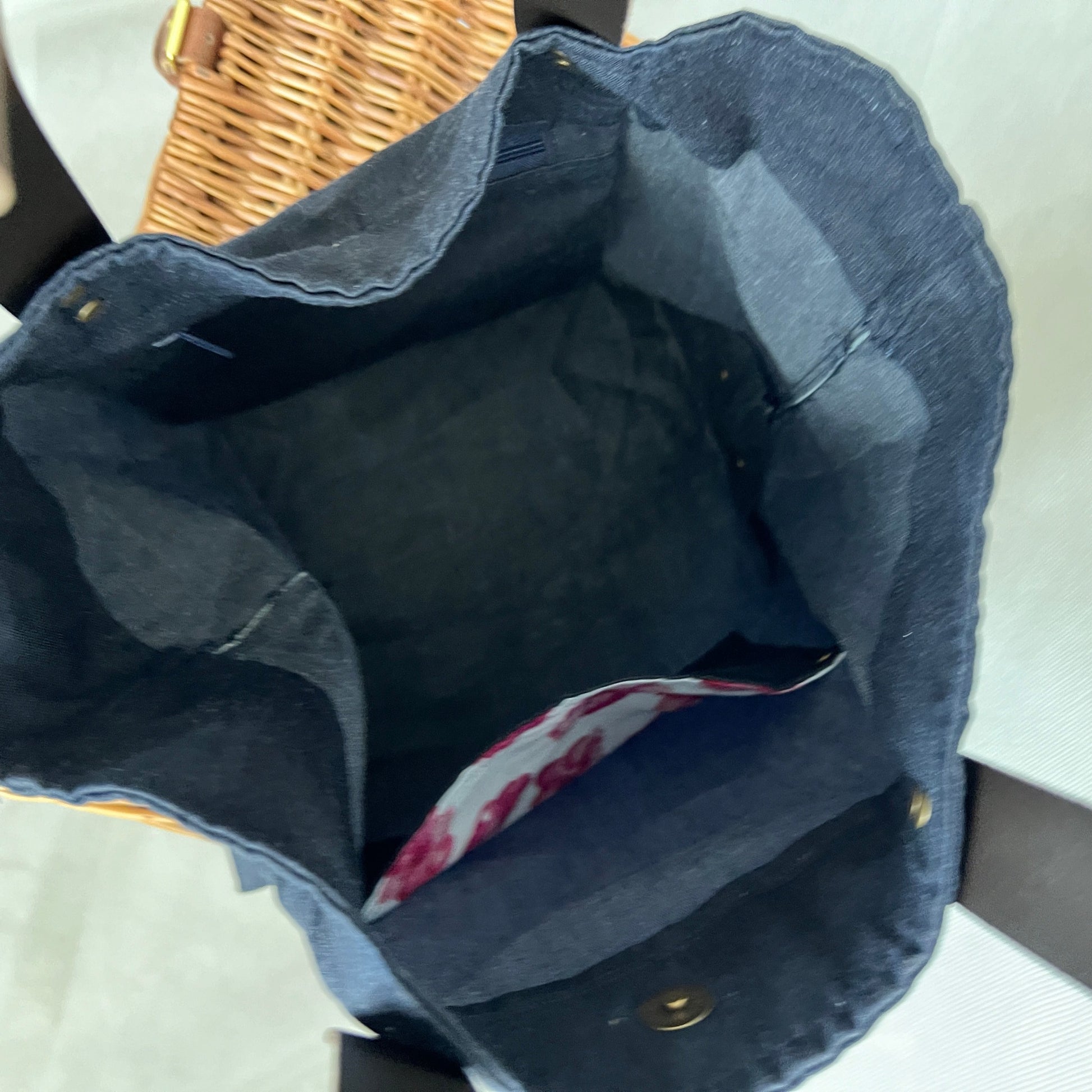 inside view of navy blue waxed canvas tote bag, one zipped pocket and one open pocket with pretty pink and red poppy contrasting lining fabric, antique brass stud detail and magnetic closure, handmade by Tallulah Riley